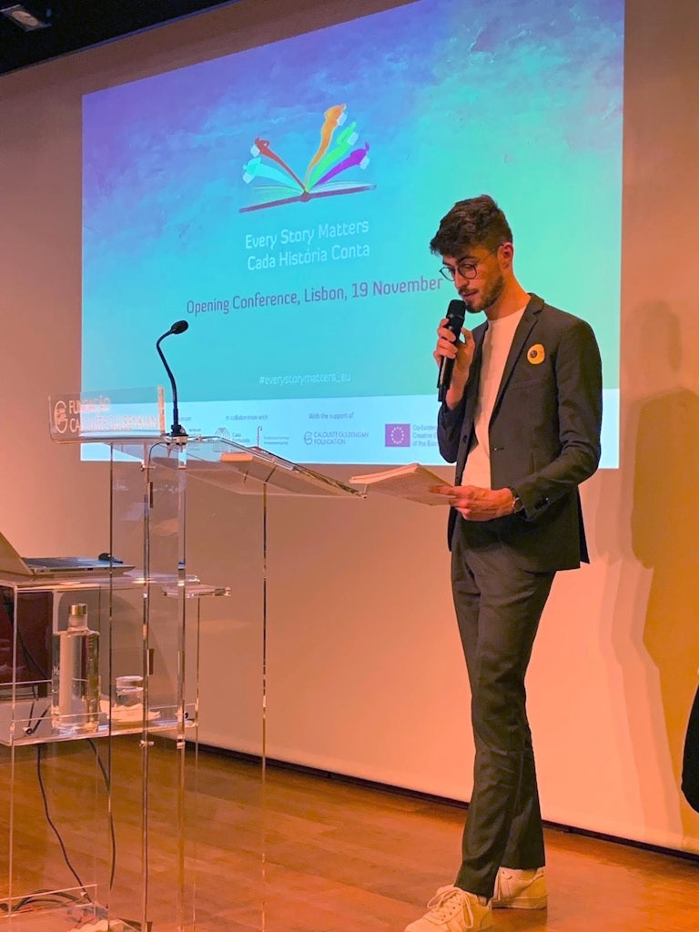 Yannick, vanuit Literatuur Vlaanderen coördinator van Every Story Matters, neemt het woord tijdens de conferentie in Lissabon.